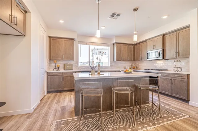a kitchen with stainless steel appliances granite countertop a sink a stove a window cabinets and a dining table chairs