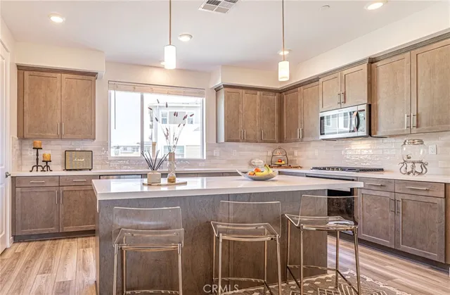 a kitchen with kitchen island granite countertop a stove top oven a sink a counter space and cabinets