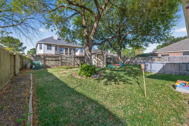 a view of a yard in front of a house with plants and large tree