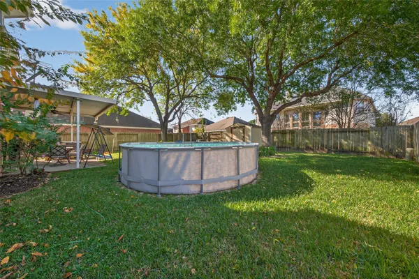 a view of a backyard with wooden fence and a large tree
