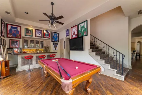 a living room with furniture pool table flat screen tv and windows