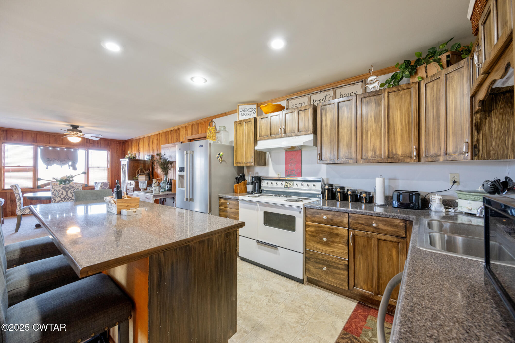 982 Lost Creek Boat Dock Road Decaturville, TN 38329 - Photo 15 of 31 a kitchen with stainless steel appliances granite countertop a stove top oven a sink dishwasher and white cabinets with wooden floor