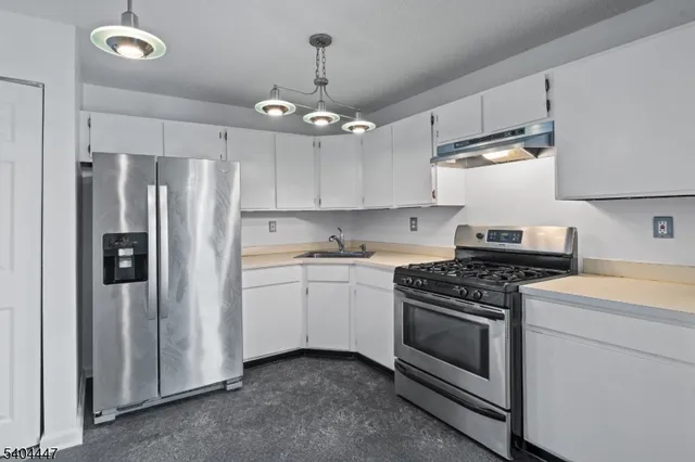 a kitchen with stainless steel appliances a stove a refrigerator and white cabinets