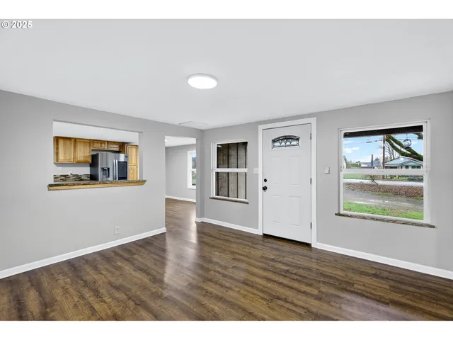 a view of an empty room with window and wooden floor
