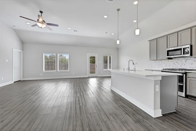 a kitchen with stainless steel appliances granite countertop a stove top oven a sink with wooden floors and cabinets