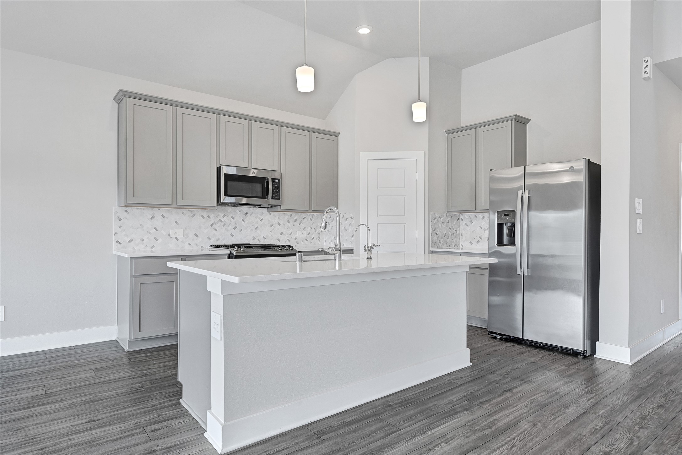 10329 South Goshawk Trail Conroe, TX 77385 - Photo 9 of 46 a kitchen with kitchen island granite countertop a refrigerator and a stove top oven