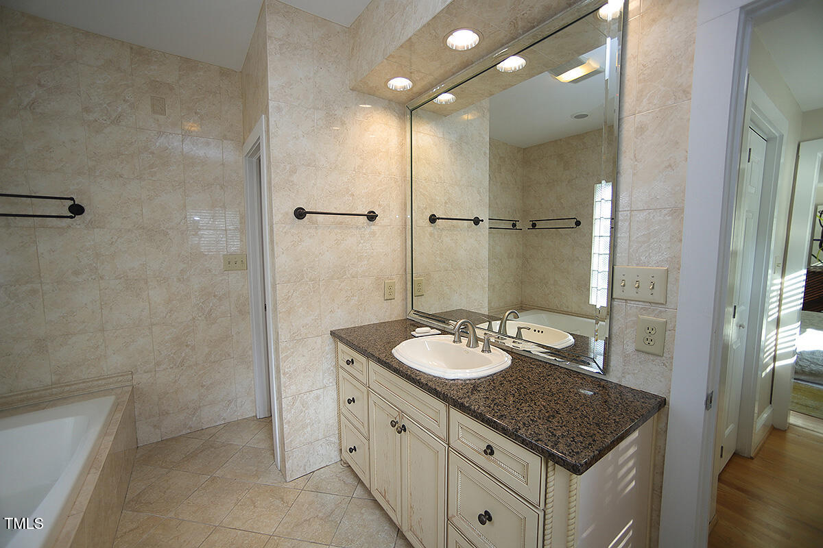 3409 White Oak Road Raleigh, NC 27609 - Photo 14 of 24 a bathroom with a granite countertop sink a toilet a mirror and shower