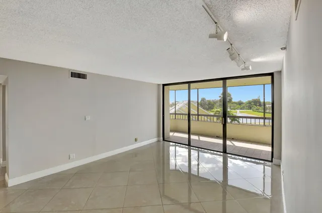 an empty room with sliding glass door and chandelier fan
