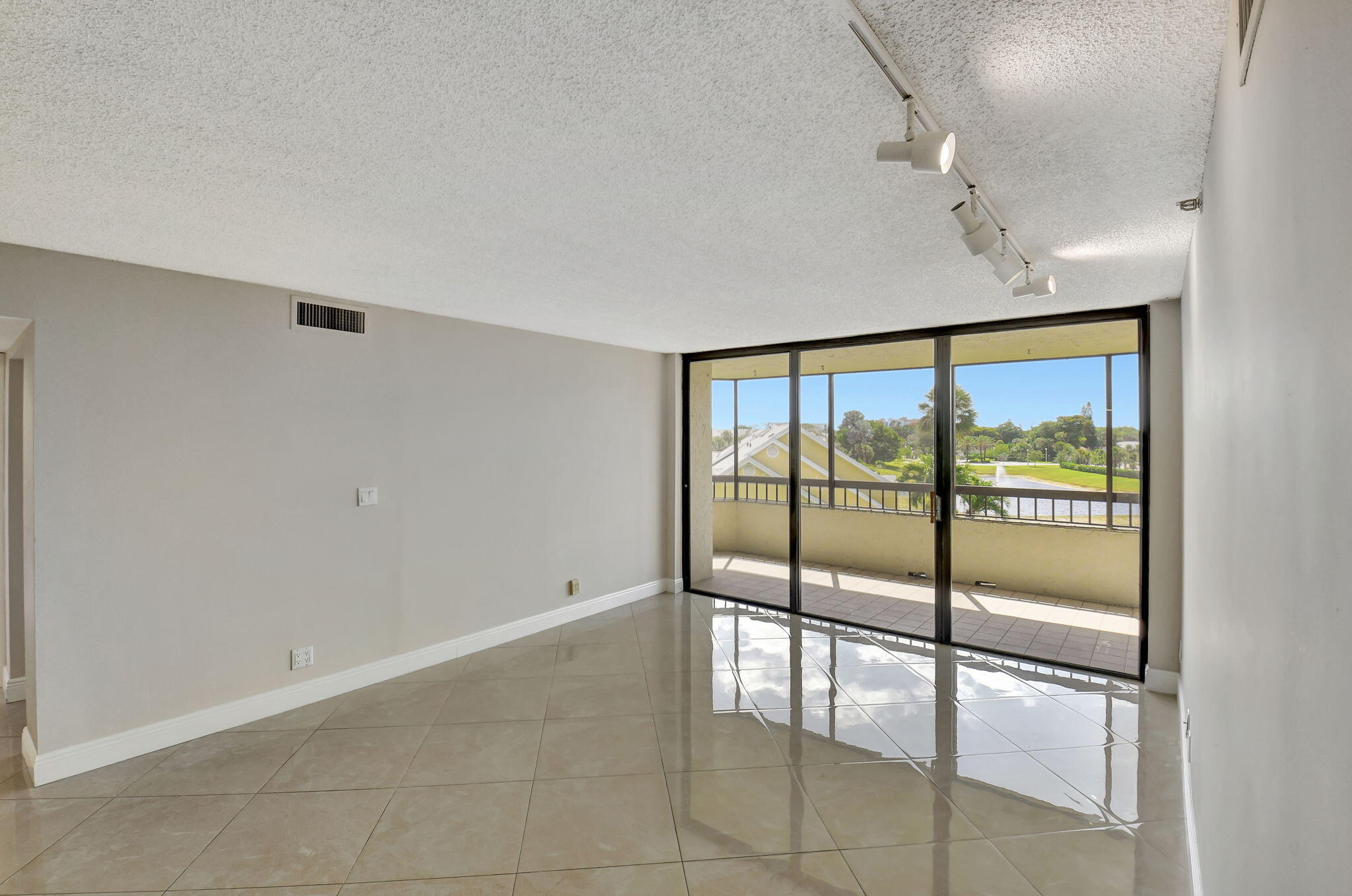 6372 La Costa Drive, Unit 302 Boca Raton, FL 33433 - Photo 20 of 52 an empty room with sliding glass door and chandelier fan