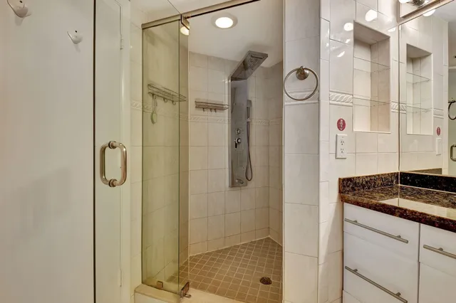 a bathroom with a double vanity sink a large mirror and shower