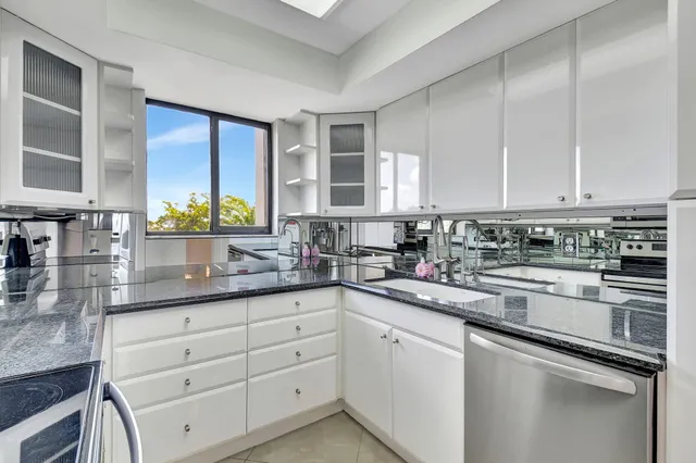 a kitchen with granite countertop white cabinets and white stainless steel appliances