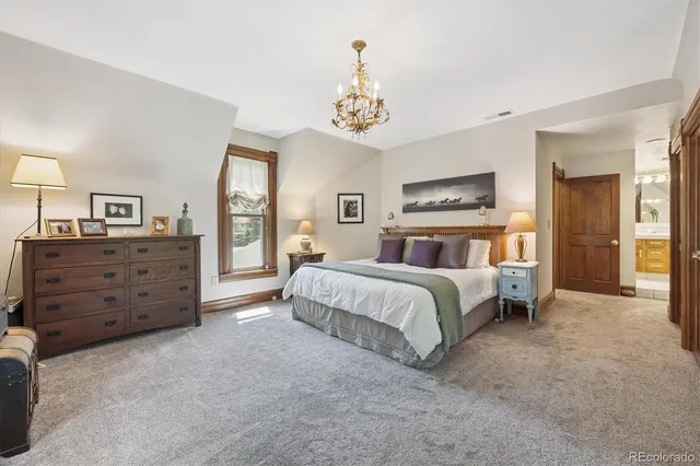 a spacious bedroom with a large bed and a chandelier
