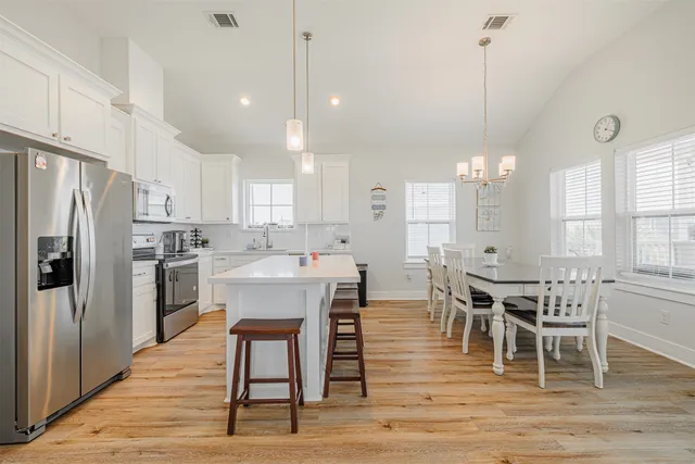 a kitchen that has a table chairs stainless steel appliances and cabinets