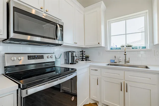 a kitchen with stainless steel appliances granite countertop a stove a refrigerator a kitchen island a sink and a living room