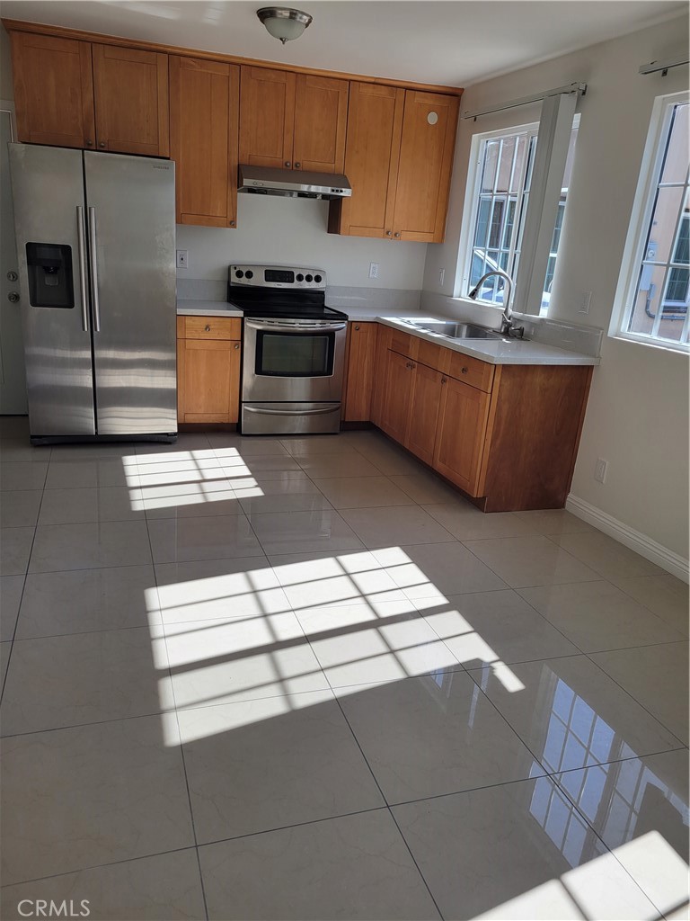 a kitchen with stainless steel appliances kitchen island granite countertop a refrigerator stove a sink and dishwasher