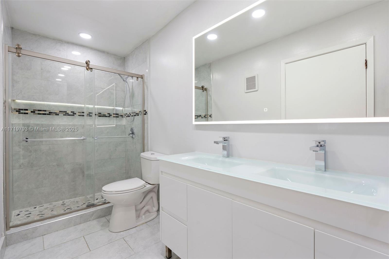 9729 Hammocks Boulevard, Unit 106E Miami, FL 33196 - Photo 12 of 25 a bathroom with a double vanity sink toilet mirror and shower