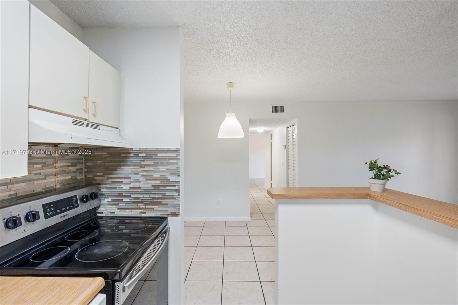 9729 Hammocks Boulevard, Unit 106E Miami, FL 33196 - Photo 20 of 25 a kitchen that has a stove and a white cabinets