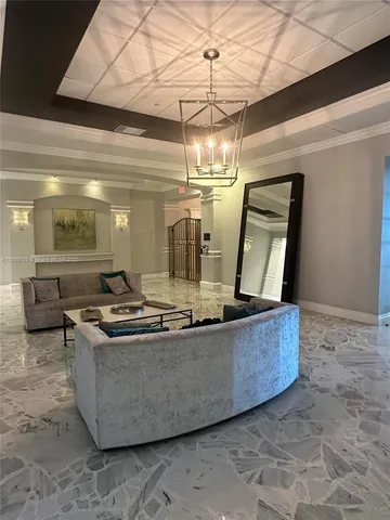 a living room with stainless steel appliances granite countertop furniture and a chandelier