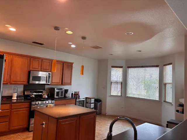 a kitchen with stainless steel appliances granite countertop a stove top oven a sink dishwasher a dining table and chairs with wooden floor