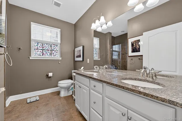 a bathroom with a granite countertop sink a toilet and a mirror