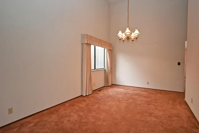 a view of an empty room with a chandelier fan