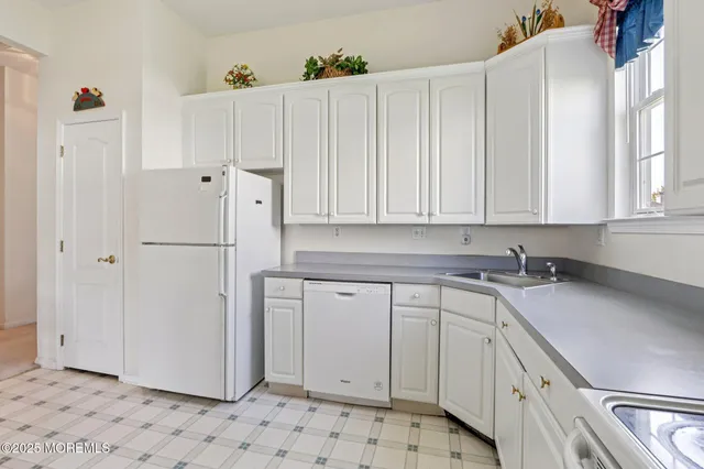 a kitchen with white cabinets and refrigerator