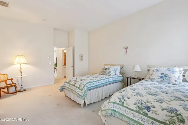 a spacious bedroom with two bed and a lamp