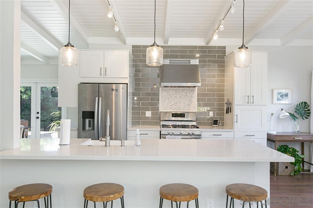 759 Bellevue Place La Jolla, CA 92037 - Photo 3 of 15 a kitchen with stainless steel appliances kitchen island granite countertop a table chairs in it and wooden floors