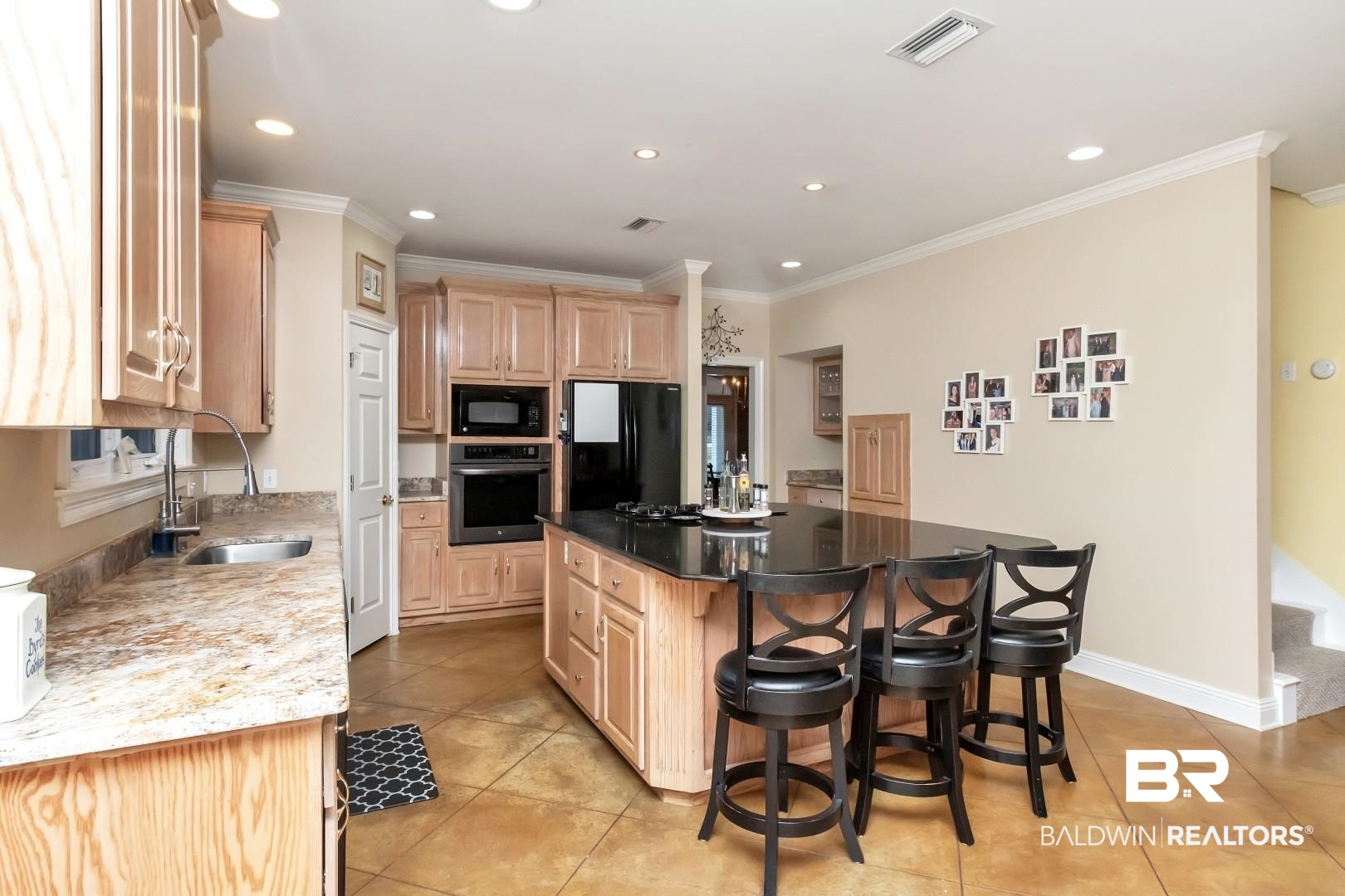 1050 Southern Way Court Mobile, AL 36609 - Photo 8 of 36 Kitchen featuring a breakfast bar, sink, a kitchen island, light stone countertops, and black appliances