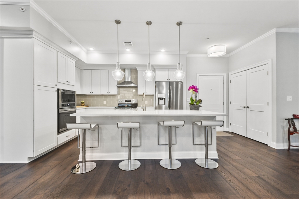 a kitchen with white cabinets and wooden floor