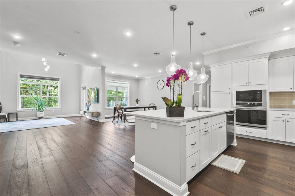 635 Old Post Road, Unit 303 Sharon, MA 02067 - Photo 3 of 33 a kitchen that has a lot of white cabinets and couches with wooden floor