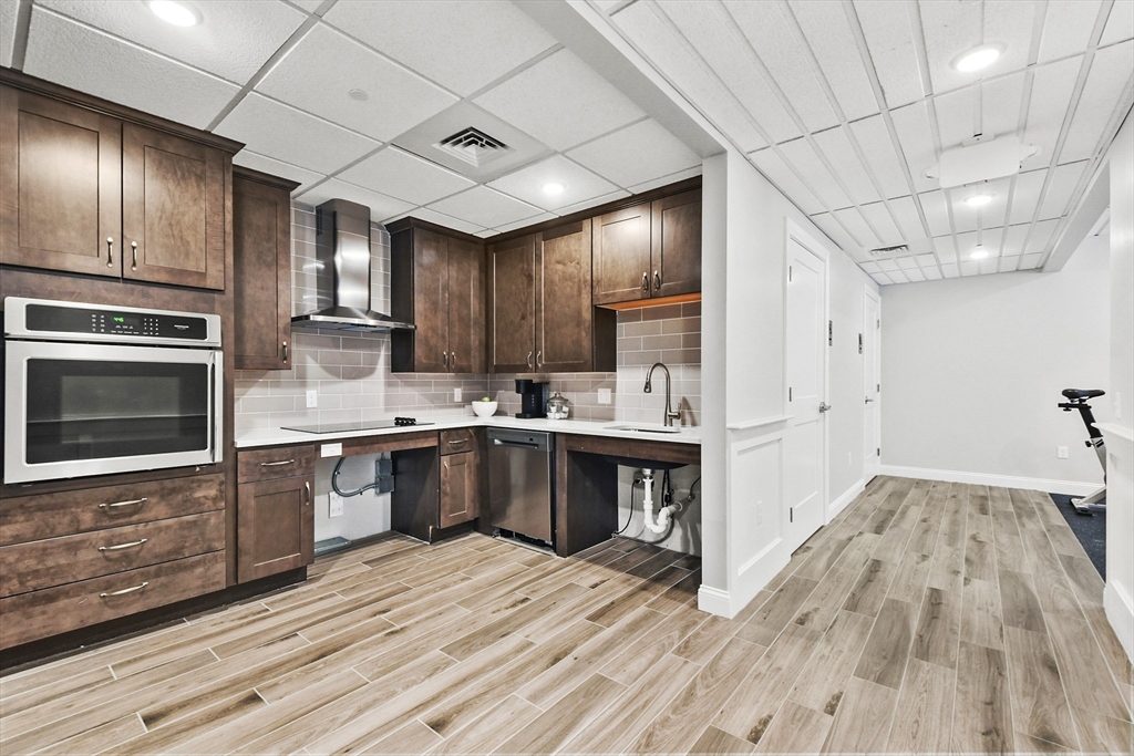 635 Old Post Road, Unit 303 Sharon, MA 02067 - Photo 33 of 33 a kitchen with granite countertop wooden floors a sink stainless steel appliances and cabinets