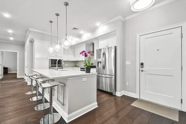 a kitchen view with stainless steel appliances a dining table chairs sink and wooden floor