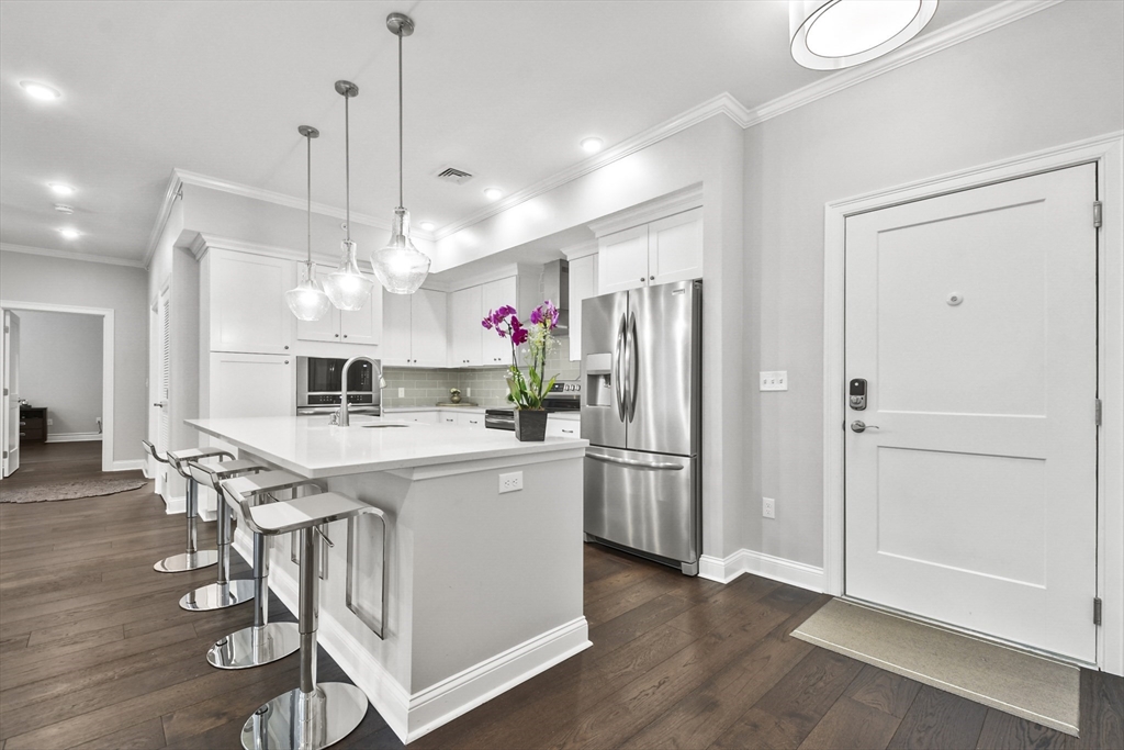 635 Old Post Road, Unit 303 Sharon, MA 02067 - Photo 5 of 33 a kitchen view with stainless steel appliances a dining table chairs sink and wooden floor