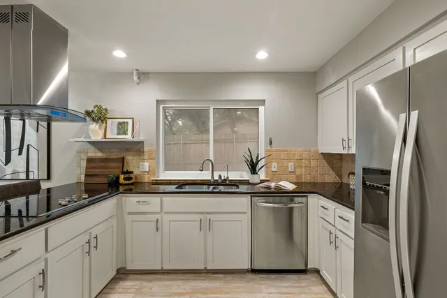 a kitchen with stainless steel appliances granite countertop a sink a stove and a refrigerator