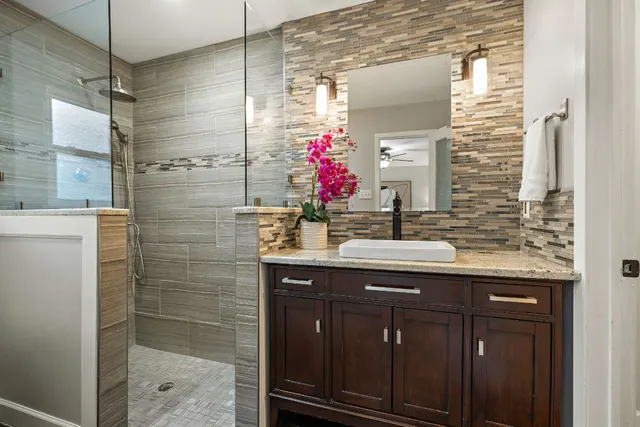 a bathroom with a granite countertop sink a shower and a mirror