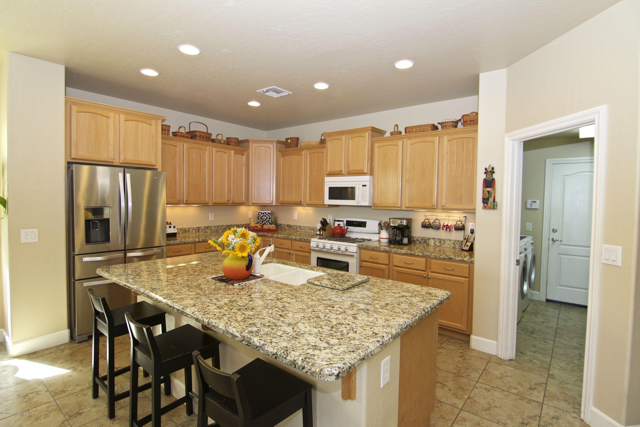 1157 Rusty Nail Road Prescott Valley, AZ 86314 - Photo 5 of 45 a kitchen with stainless steel appliances granite countertop a table chairs sink refrigerator and microwave