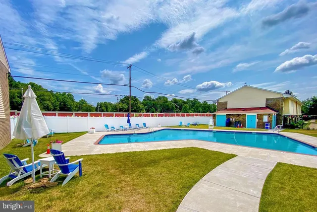 a view of swimming pool with seating area and trees in the background