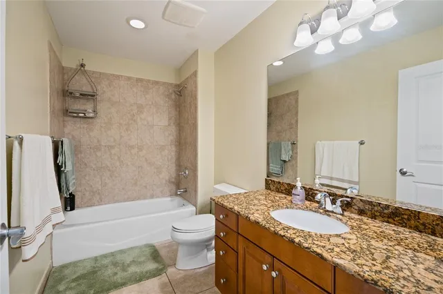 a bathroom with a granite countertop sink a toilet and bathtub