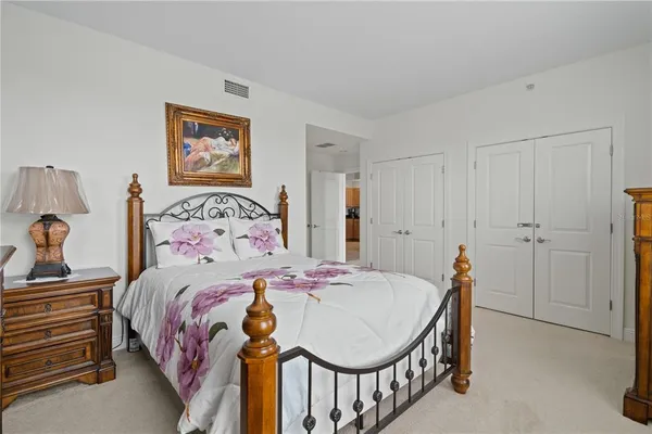 a bedroom with a bed a dresser and painting on the wall