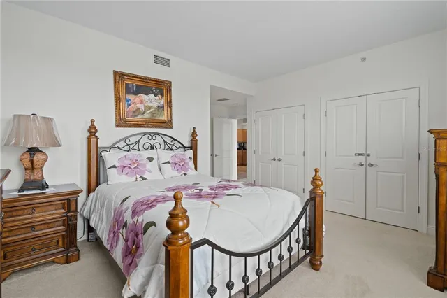 a bedroom with a bed a dresser and painting on the wall