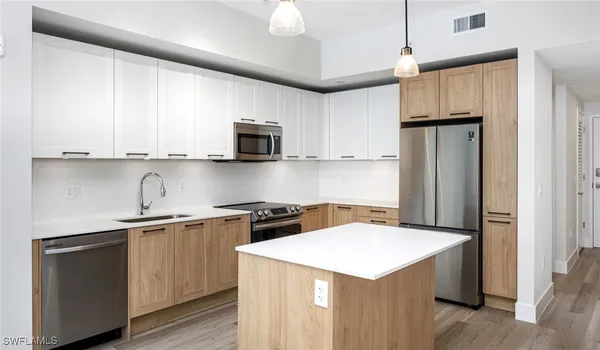 a kitchen with stainless steel appliances a sink a stove a refrigerator cabinets and a window