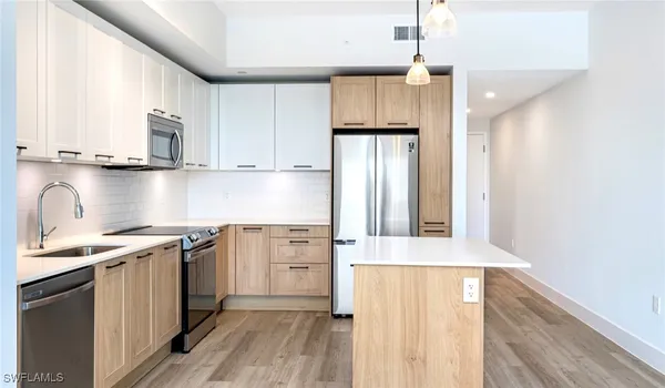 a kitchen with stainless steel appliances granite countertop a refrigerator a sink dishwasher a stove with wooden cabinets