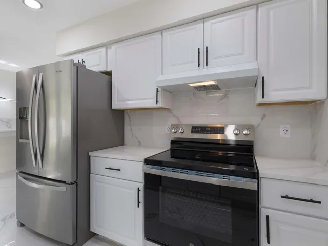 a kitchen with refrigerator a stove and white cabinets