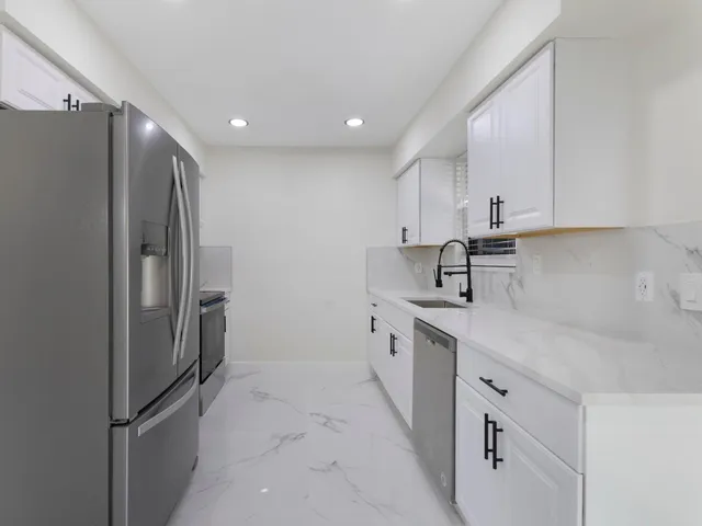 a kitchen with white cabinets and stainless steel appliances