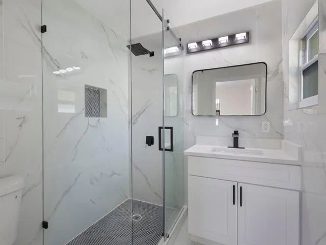 a bathroom with a toilet sink vanity and shower