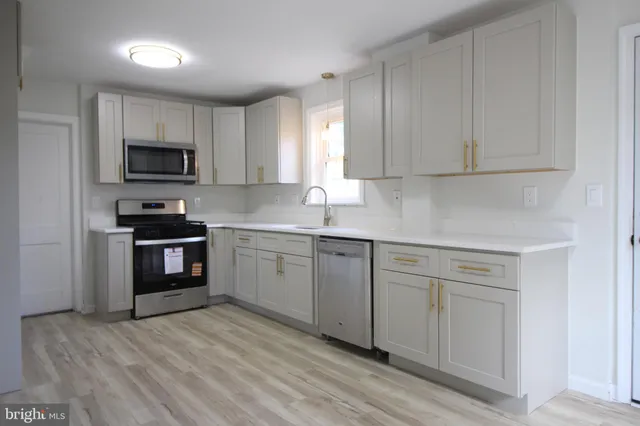 a kitchen with granite countertop white cabinets stainless steel appliances and a sink
