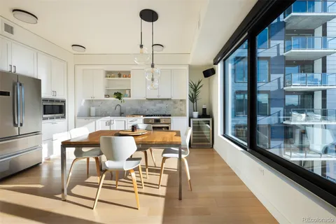a dining room with stainless steel appliances kitchen island granite countertop a table chairs and a glass door
