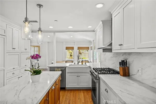 a kitchen that has a lot of white cabinets and stainless steel appliances