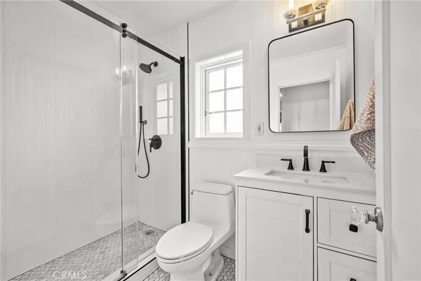 a bathroom with a granite countertop toilet sink shower and mirror
